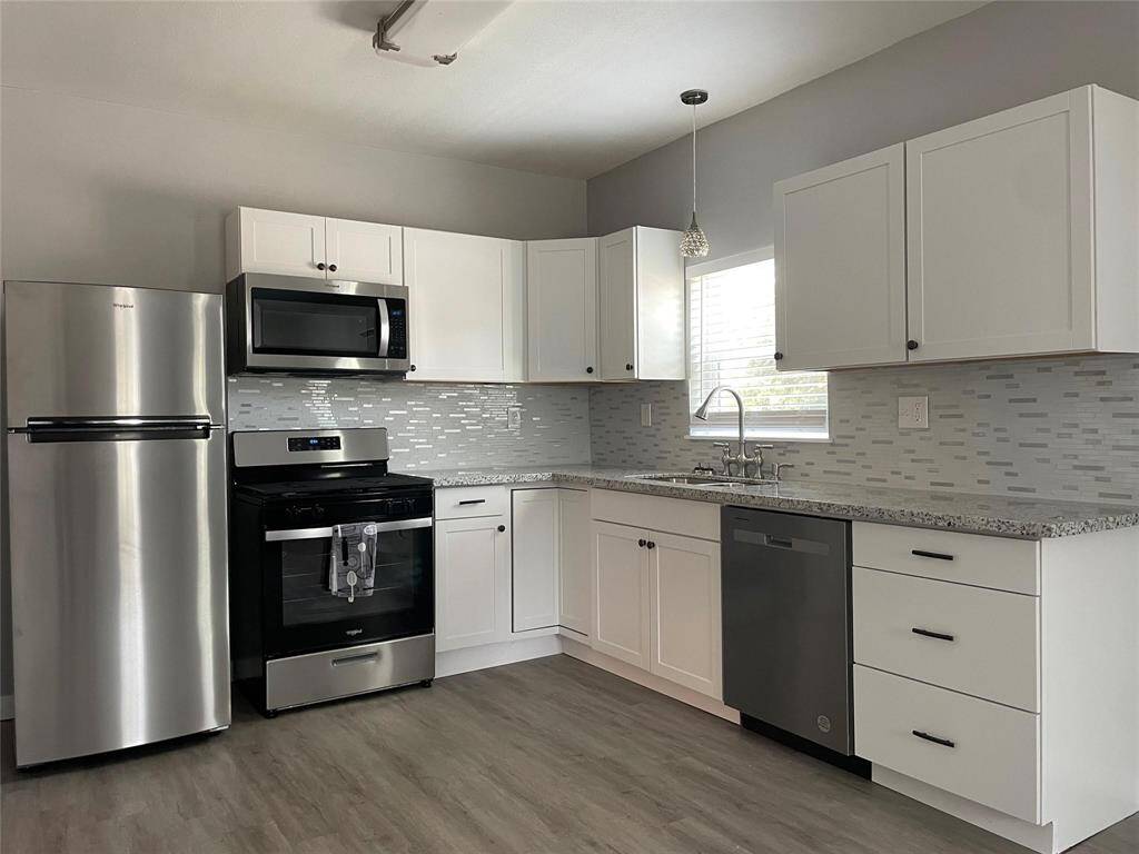 Spacious kitchen with modern backsplash, ample cabinet space and gorgeous flooring.