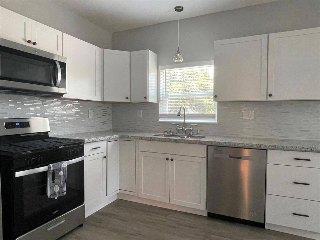 Gorgeous kitchen with custom backsplash, Whirlpool appliances, designer cabinetry and modern pendant lighting.