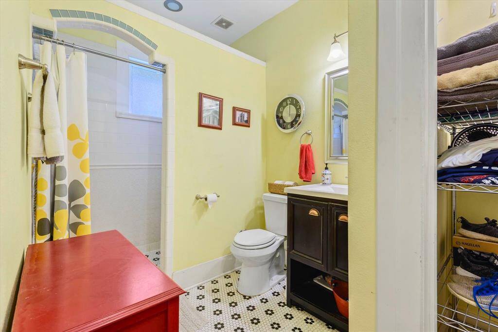 Enjoy timeless charm in this well-appointed master bathroom, featuring vintage-style hex tile flooring, a stylish vanity with bronze hardware, and a spacious walk-in shower with tile accents and arched detailing