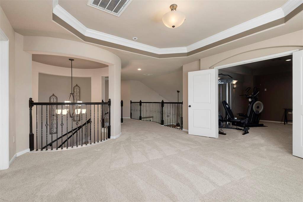 View of game room, catwalk with pretty iron banisters plus view of the media room with double door entrance.