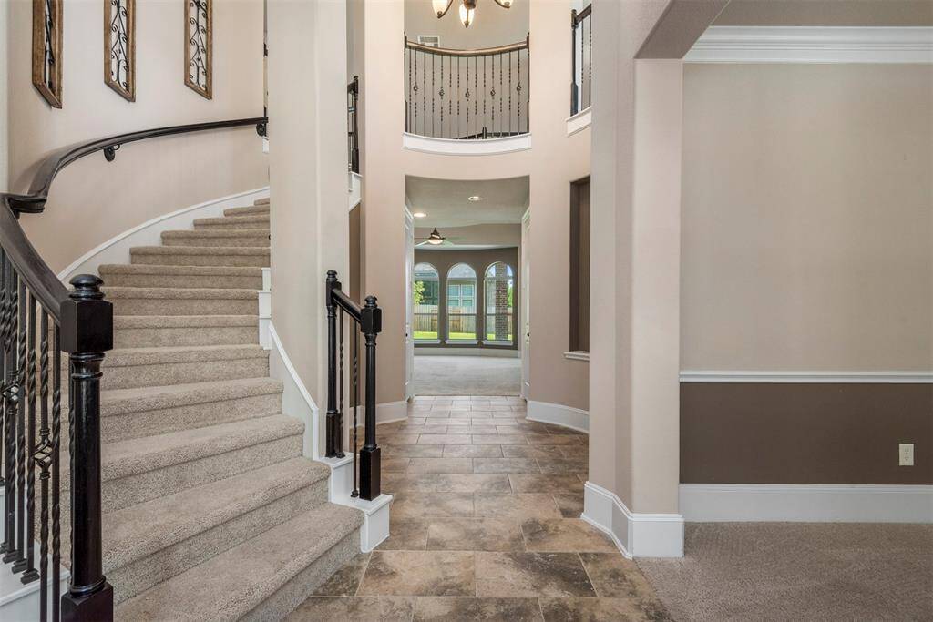 Impressive, grand entrance with 25-foot rotunda ceiling, gorgeous winding staircase and pretty neutral tile floors.