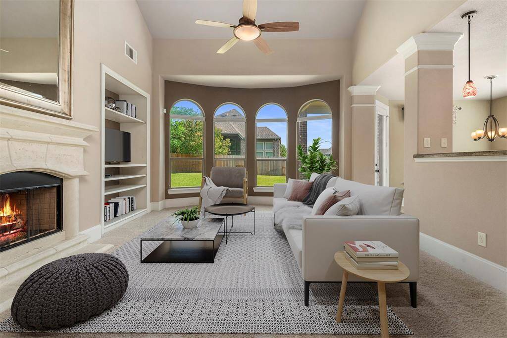 Sun drenched family room with a wall of arched windows with custom window blinds, built ins and a cozy fireplace (gas log or woodburning). Virtually staged.