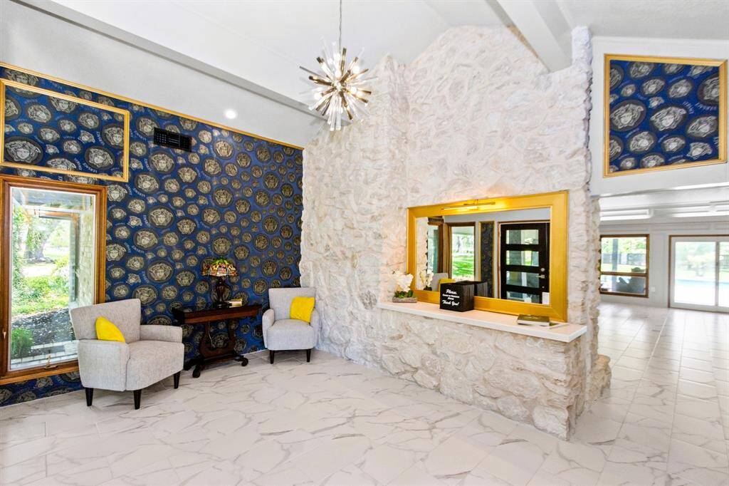 The foyer boasts sleek stone floors and striking wallpaper, setting a tone of luxury and sophistication.