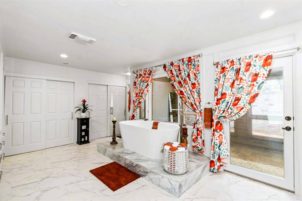 The sleek primary bath features a large soaking tub, bathed in natural light, creating a serene and stylish retreat.