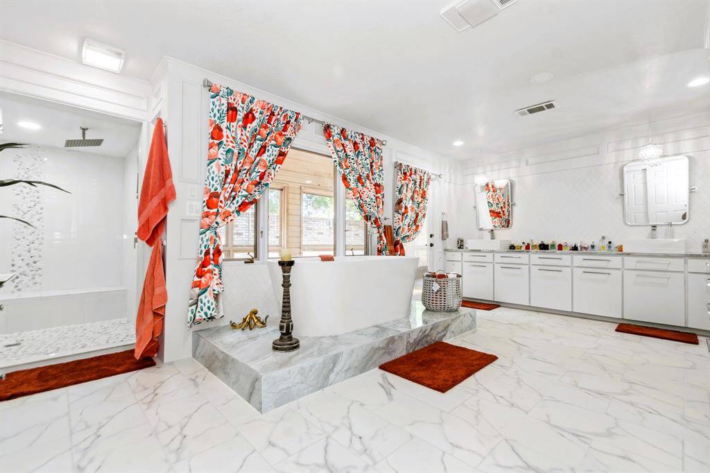 The chic primary bath boasts a spacious soaking tub, abundant natural light, and dual sinks, offering both luxury and practicality.