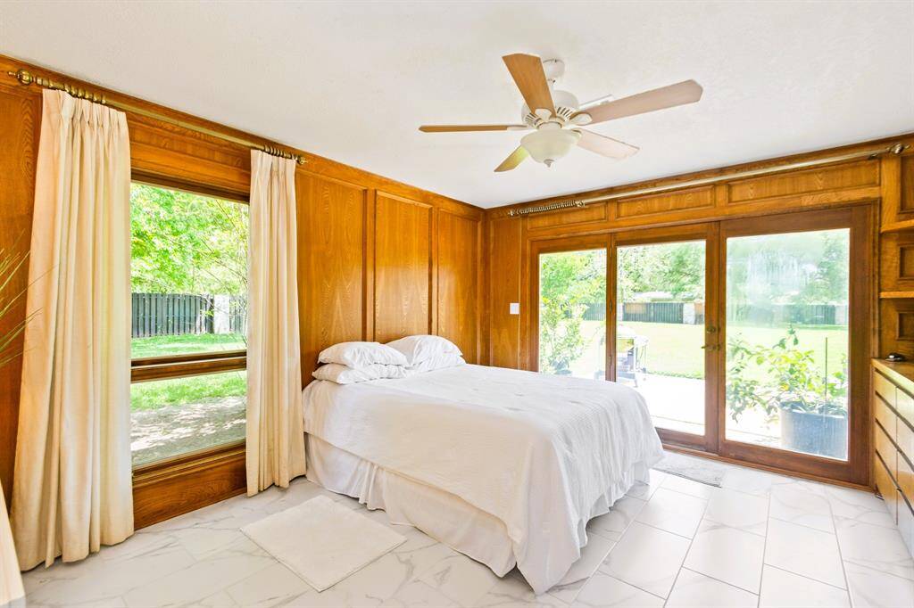 This guest house bedroom offers a beautiful view of the backyard, complemented by elegant built-in cabinets for added convenience and style.