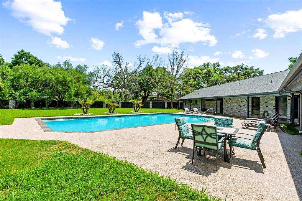 The sparkling pool is inviting and perfectly complemented by an expansive backyard, offering plenty of space for relaxation and recreation.