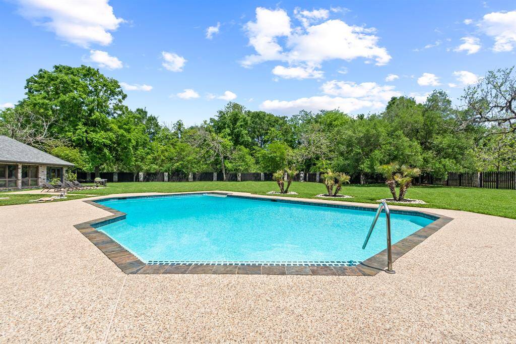 The sparkling, inviting pool sits in a fully fenced backyard, offering tons of space for relaxation and outdoor activities.