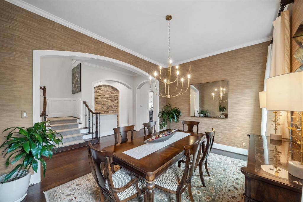 Don't these sellers have impeccable taste! This elegant dining room showcases beautiful designer wallpaper, rich wood floors, intricate crown molding, and a stunning chandelier, creating a sophisticated and inviting space for gatherings. The large mirrors that flank the dining table convey.
