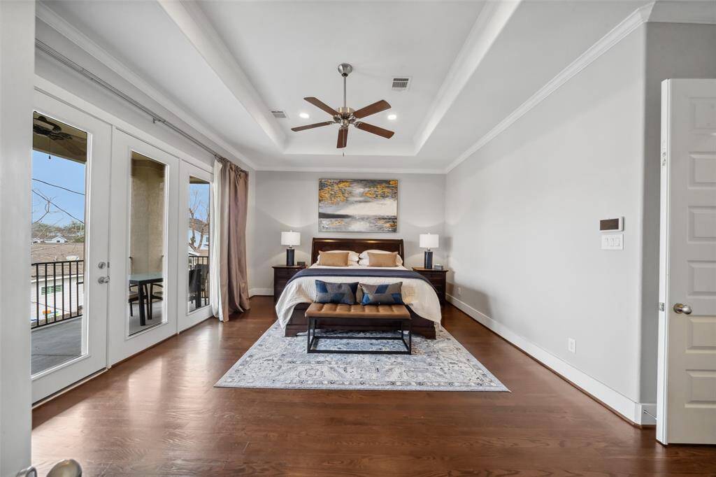 The primary ensuite is a luxurious retreat, featuring wood floors, a tray ceiling, recessed lighting, and a spa-like bath. The HUGE walk-in closet offers ample storage, while the doors on the left lead to a cozy private balcony, perfect for enjoying a peaceful moment outdoors.