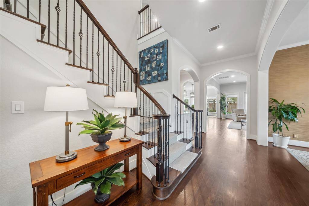 Upon entry you are greeted by this grand staircase featuring solid wood risers, a removable designer stair runner, and iron balusters, creating a dramatic and welcoming first impression.
