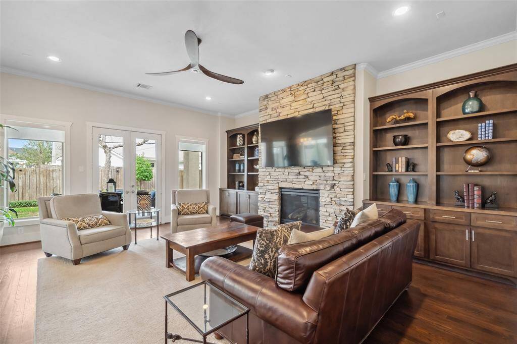 The sizable living room boasts rich wood floors, elegant lighting, and a stunning stone fireplace, creating a warm and inviting atmosphere. Enjoy seamless indoor-outdoor living with easy access to the backyard through a spacious veranda.