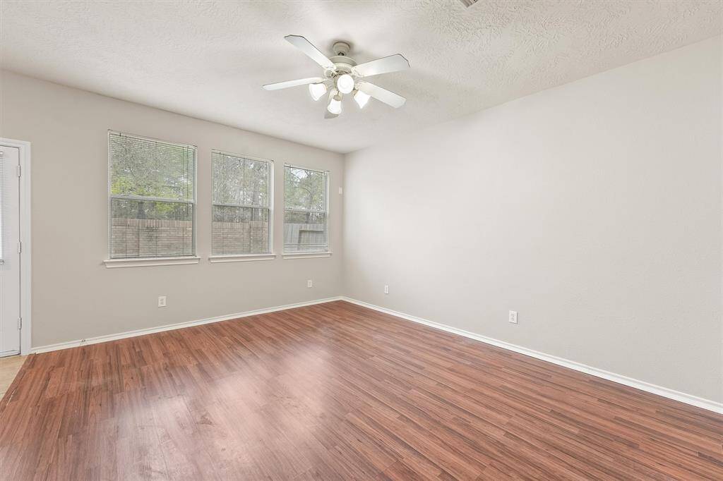 Wood lanimate flooring in the living room with 3 large windows looking into the backyard
