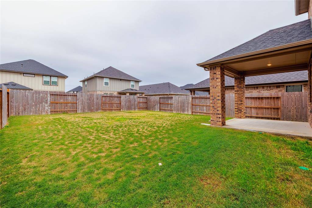 Spacious backyard with a covered patio, surrounded by a wooden privacy fence, ideal for outdoor activities and relaxation.