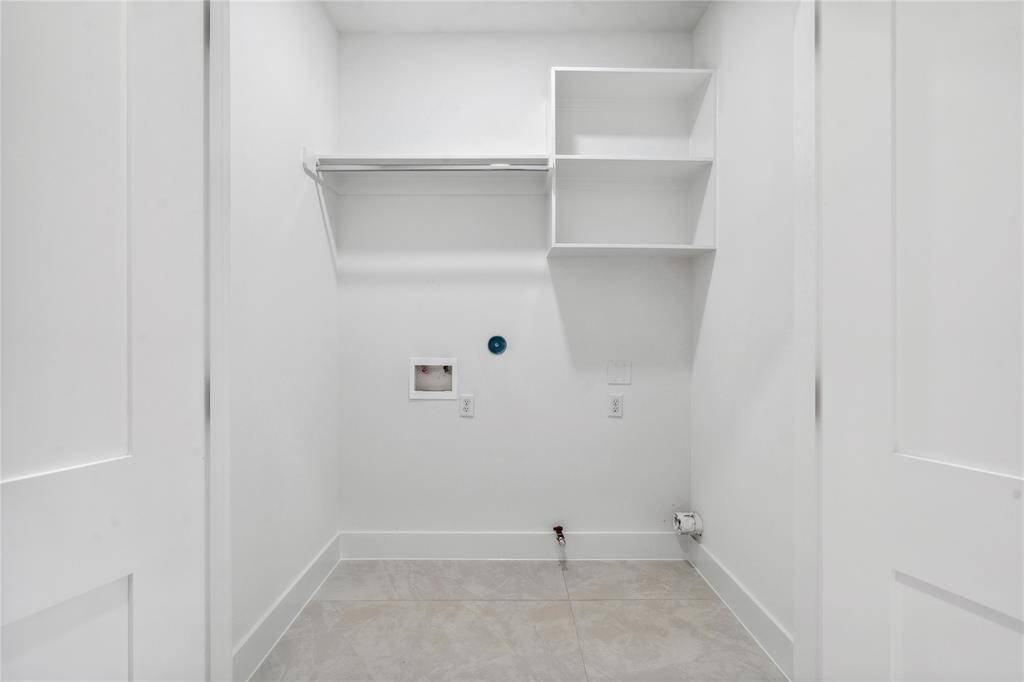 A walk in utility room is spacious with custom shelves and hanging rack.