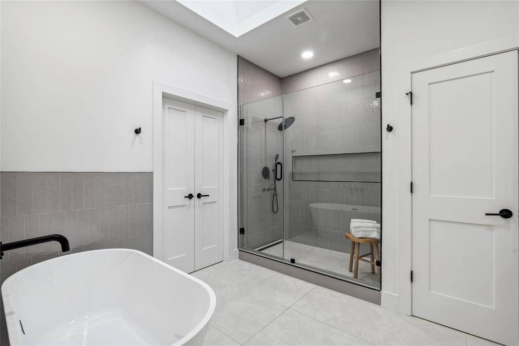 A stunning, frameless, oversized walk-in shower with an oversize shampoo niche.