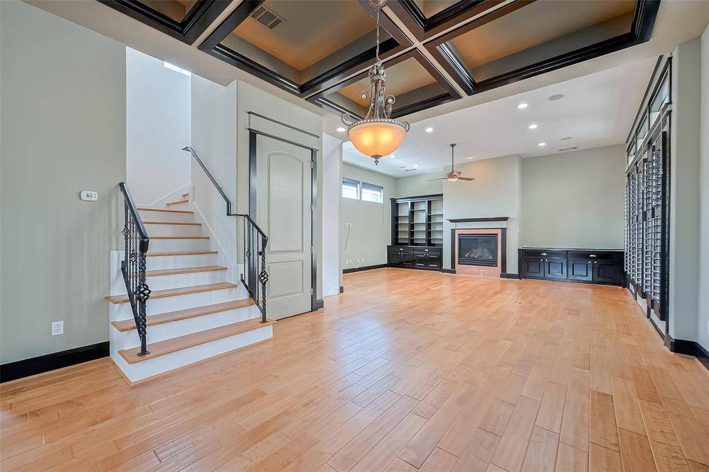 The dining area blends seamlessly between kitchen and living spaces, crowned by a ceiling with bold geometric recesses and dark trim. Statement lighting sets the tone for intimate meals or festive gatherings.