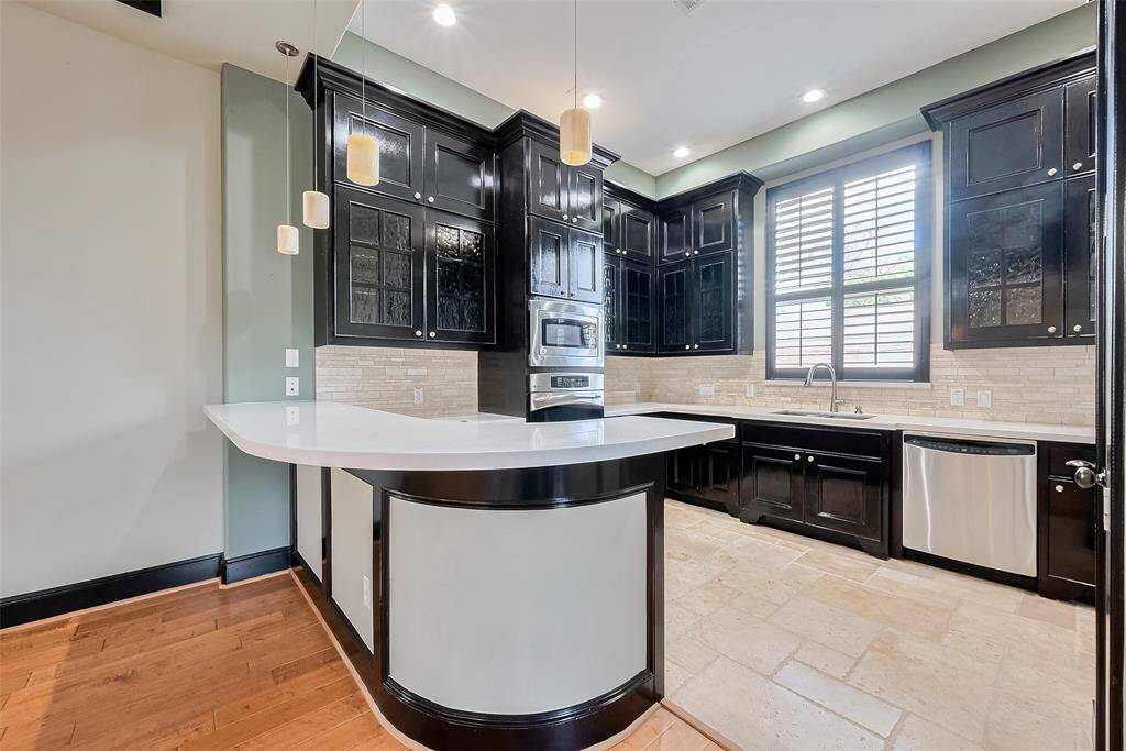 A stunning culinary space, the kitchen offers ample dark cabinetry, granite counters, and a graceful curve in the peninsula for casual seating. Contrasting trim and modern lighting give this space polish and presence.
