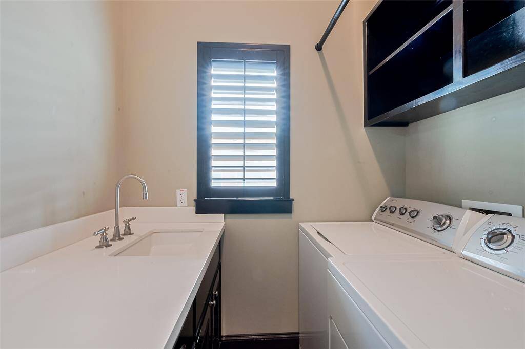 This laundry space combines practicality with thoughtful detail: a wide countertop for folding, cabinetry for storage, and a window trimmed in deep tones that ties into the home’s cohesive design.