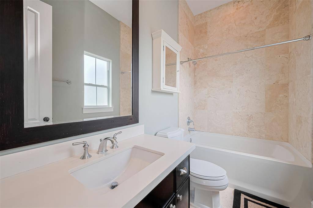 This attached bath offers a shower/tub combination, a sleek vanity, and a large mirror—balancing everyday utility with understated elegance.