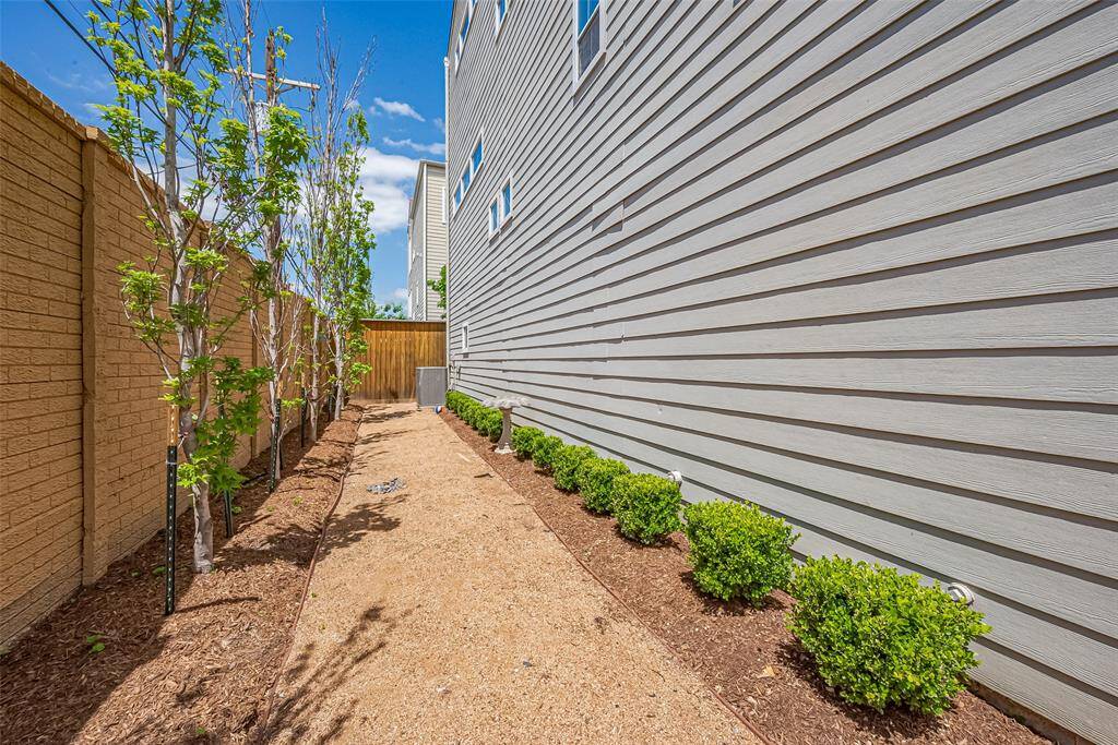The fenced backyard extends the living space outdoors, bordered by garden beds and the home’s tasteful exterior.