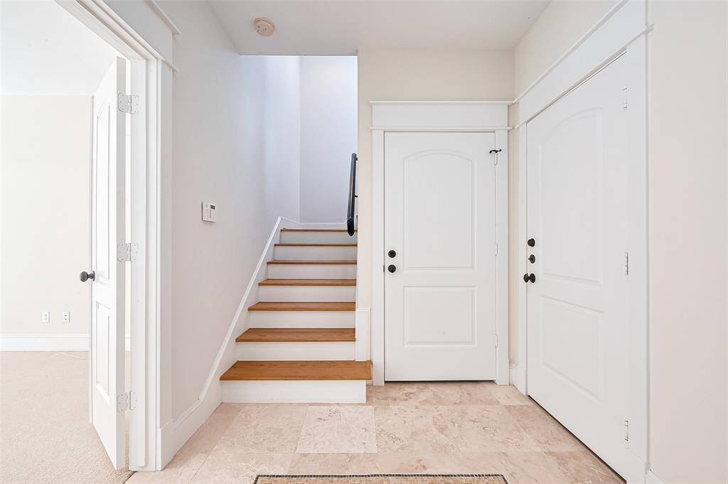 Step inside to a bright and inviting entry hall where clean sightlines reveal a bedroom to the left and a handsome staircase straight ahead. Natural light and thoughtful layout provide an immediate sense of openness.