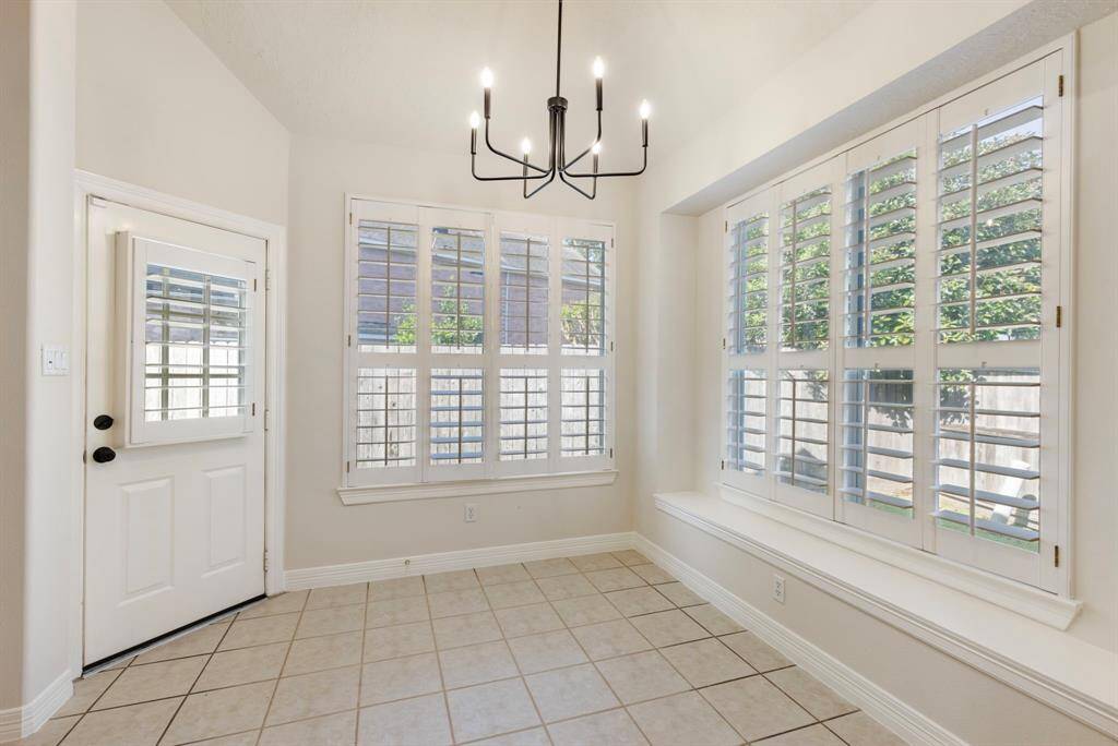 The breakfast area is light and bright with walls of windows overlooking the backyard through plantation shuttes plus an updated light fixture for a modern feel.