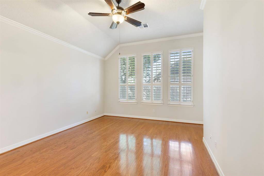 This spacious primary suite is privately tucked away on the first floor and features a wall of windows overlooking the backyard through plantation shutters.