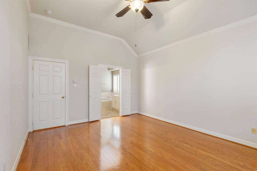 The primary suite boasts high vaulted ceilings with ceiling fan, crown moulding and plenty of space for your oversized furniture.