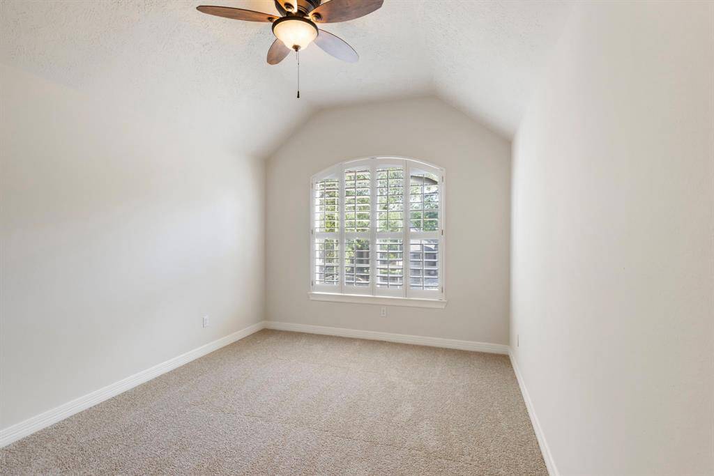 One of two secondary bedrooms upstairs featuring brand new carpet, high vaulted ceilings and plantation shutters.