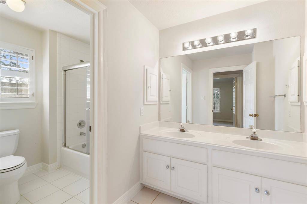 Secondary bathroom upstairs with double sinks and tile floors.