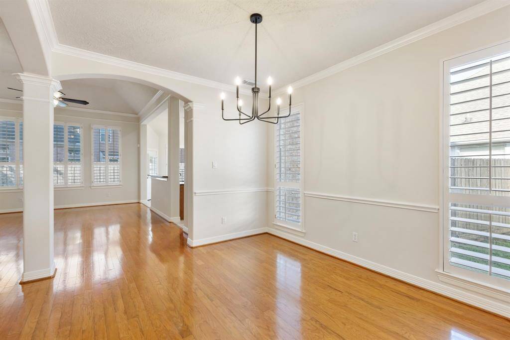 Formal dining room with crown moulding, chair rail, plantation shutters and updated light fixture.
