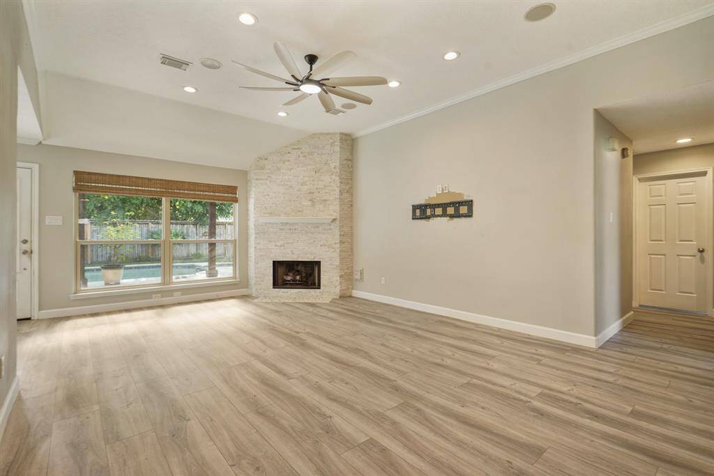 Experience the inviting living area featuring recessed lighting, a ceiling fan, and a stone fireplace. Enjoy backyard views and the underground pool through expansive windows.