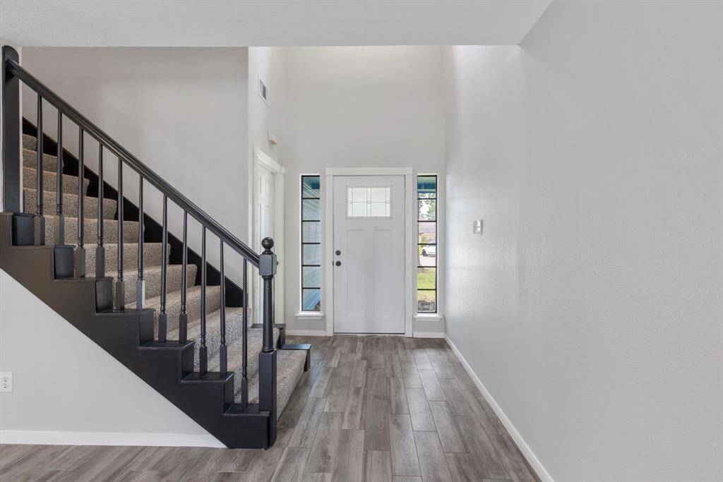 The living room boasts with warm tile plank flooring, inviting neutral paint colors, a cozy fireplace, and a ceiling fan, creating a perfect blend of comfort and charm