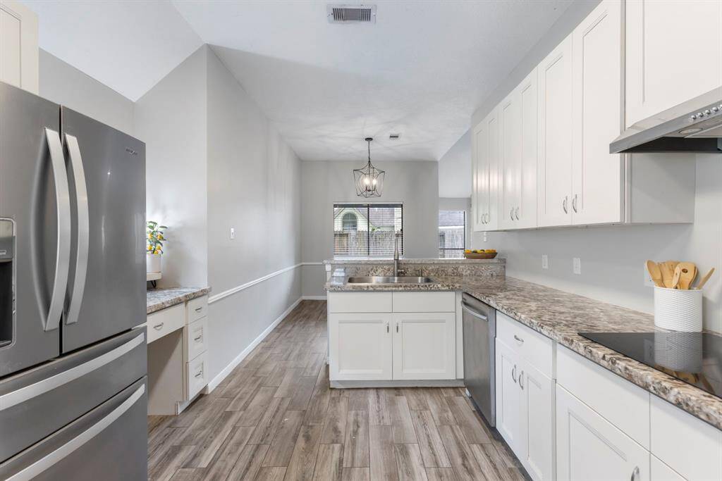 The updated kitchen features white cabinets with ample storage, complemented by granite countertops and modern stainless-steel appliances