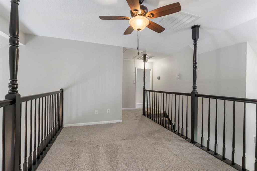 This downstairs secondary bedroom features new carpet, fresh paint, and a ceiling fan for added comfort