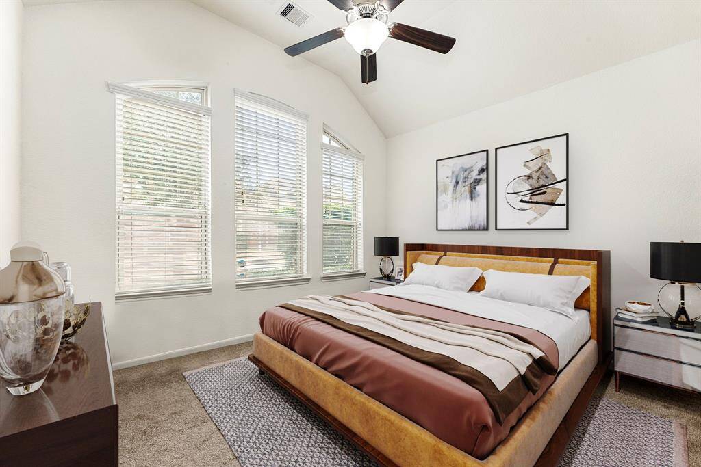 Secondary bedroom features plush carpet, neutral paint, dark stained ceiling fan with lighting and a large window with privacy blinds.