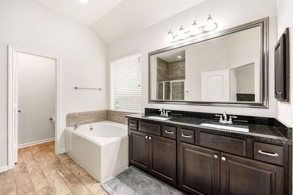 This primary bathroom is definitely move-in ready! Featuring a spa like oversized walk-in shower with custom tile surround, separate garden tub for soaking after a long day with custom tile detailing, dark stained cabinets with granite countertops, spacious walk-in closet with shelving, high ceilings, custom paint, sleek and modern finishes.