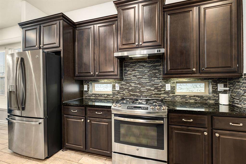 This kitchen is by far any chef’s dream! This spacious kitchen features high ceilings, dark stained wood cabinets, granite countertops, SS appliances, modern tile backsplash, recessed lighting with additional custom pendant lighting, extended counter space, granite kitchen island with double sink and space for breakfast bar and a large pantry all overlooking your huge family room.