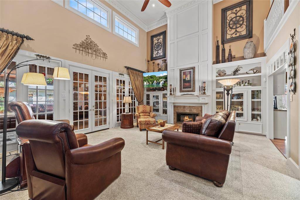Spacious living room measures 23.9 x 18.11 features high ceilings and abundant natural light, with elegant French doors leading to the backyard. It includes a fireplace, creating a warm and inviting atmosphere.