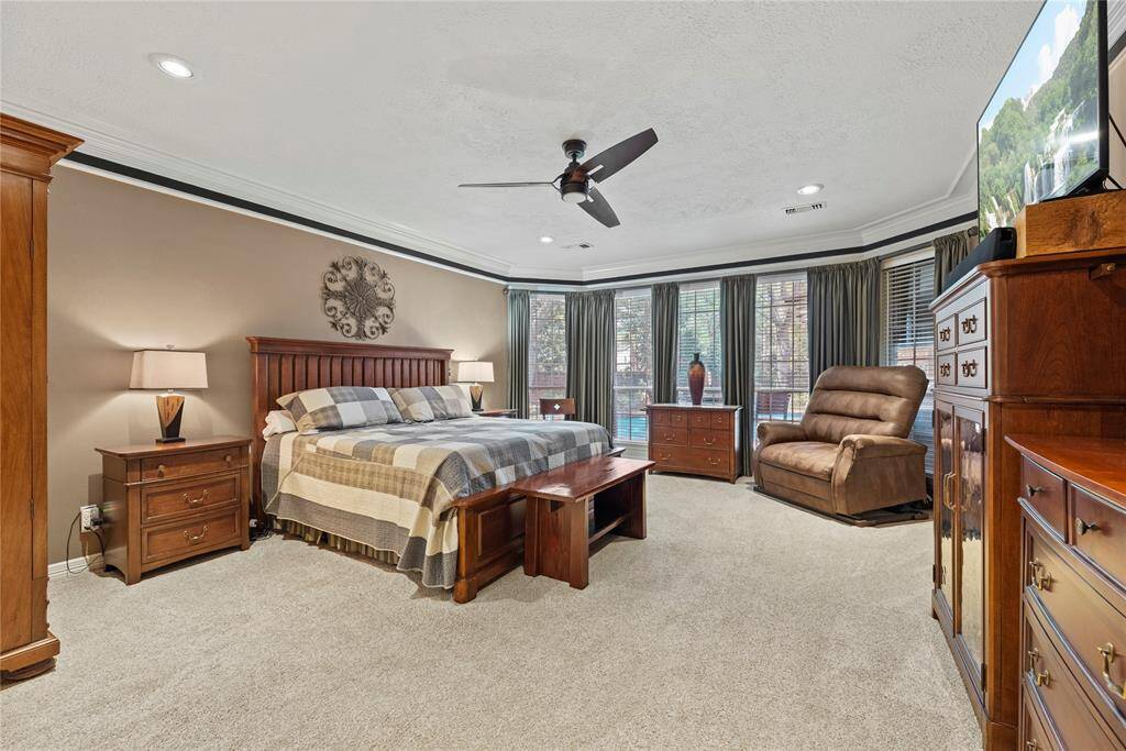 Spacious primary bedroom measures 16.3 x 26.1 is located in the first floor. It features carpet flooring, large bay windows with elegant drapes, and ceiling fan.