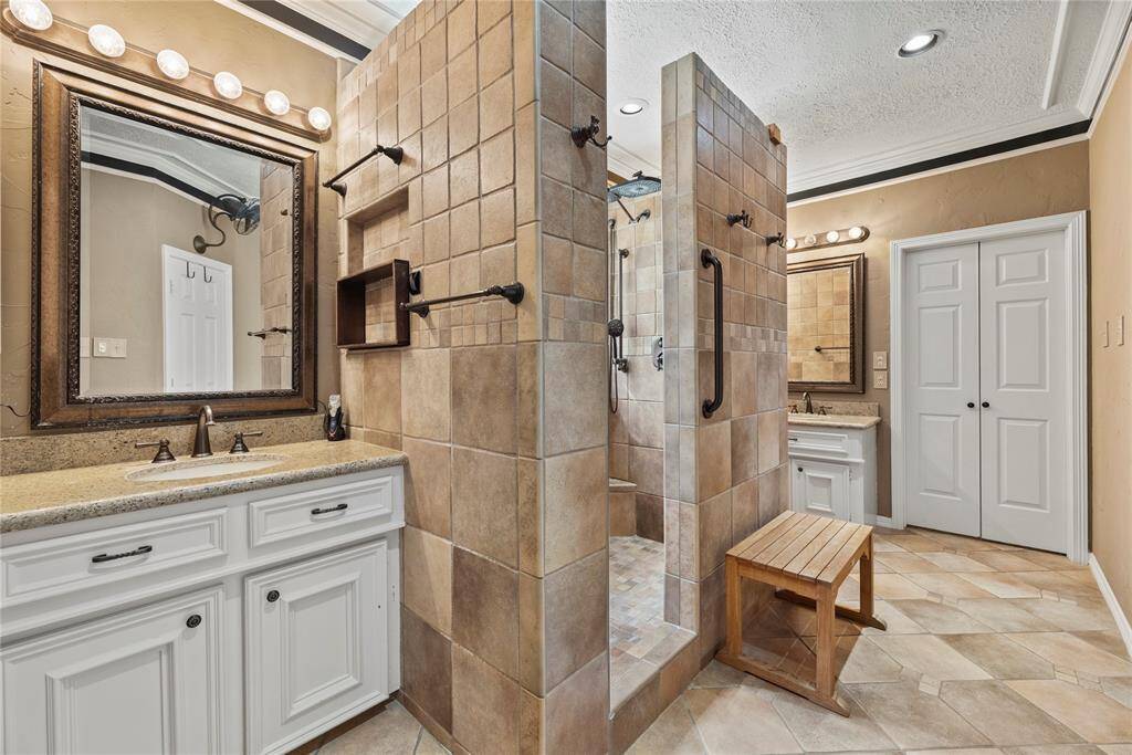 Primary bathroom features a spacious double vanity with elegant mirrors. Large walk-in shower with tiled walls.