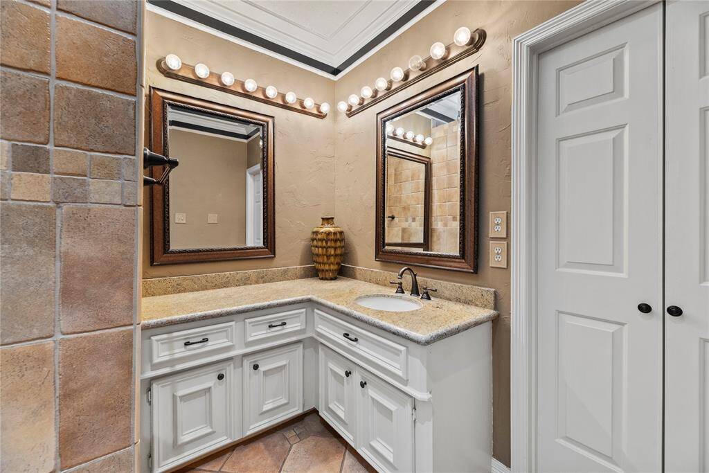 Corner vanity in the primary bathroom with a single sink, surrounded by ample counter space and storage in white cabinets.