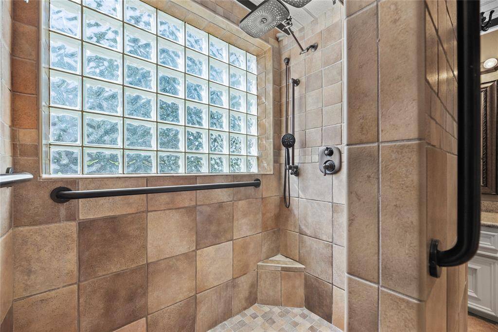 Primary bathroom shower area with elegant glass block window for natural light.