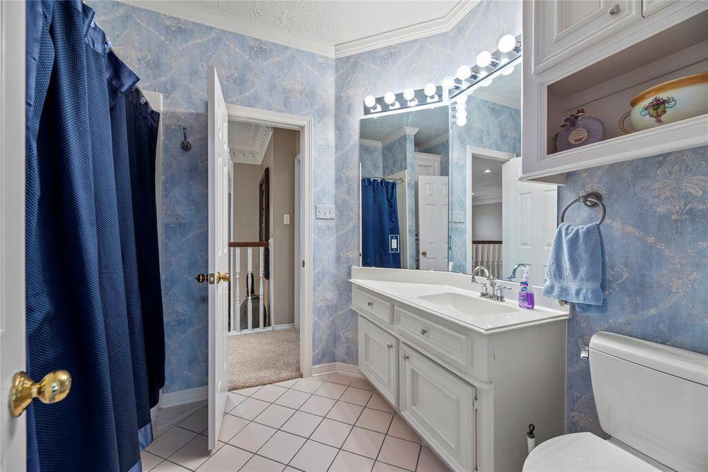 Bathroom featuring a double vanity with storage and bright lighting. It includes a shower and tiled flooring.