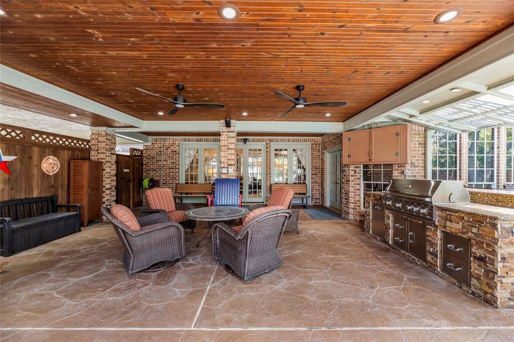 Spacious outdoor patio measures 23.6 x 21.10. The space features a wooden ceiling with recessed lighting and ceiling fans, and a built-in stone and stainless steel grill area, perfect for entertaining.