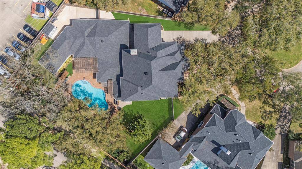 Aerial view of the property. It measures a generous 18,935 sqft lot and the house is 5,415 sqft. The backyard includes a deck area and an inviting swimming pool. The home is situated in a serene neighborhood, offering ample privacy and driveway space.