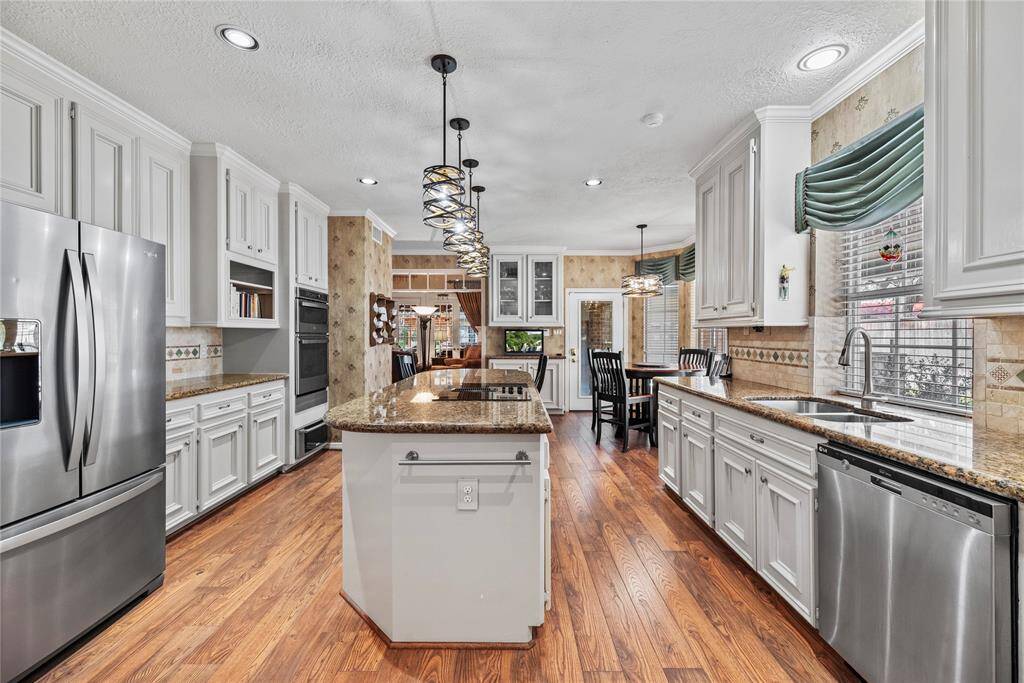 Spacious kitchen measures 15.4 x 15.5 features elegant cabinetry, granite countertops, and stainless steel appliances. It includes a central island.