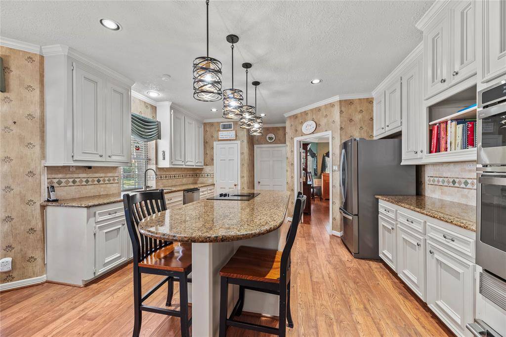 Another view of the kitchen featuring the central island and elegant lighting. Look at those cabinets and storage!