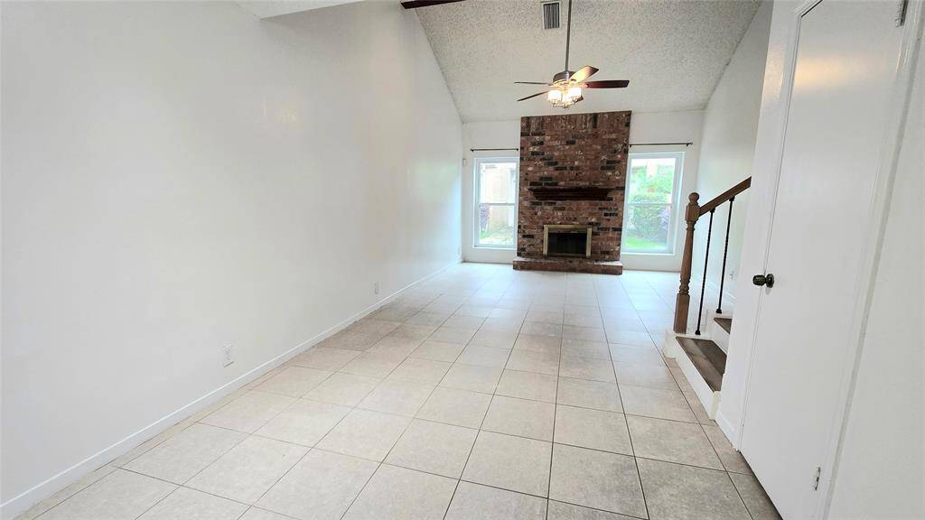 Another angle of the spacious living area showcasing its high ceilings and a cozy wood-burning fireplace.
